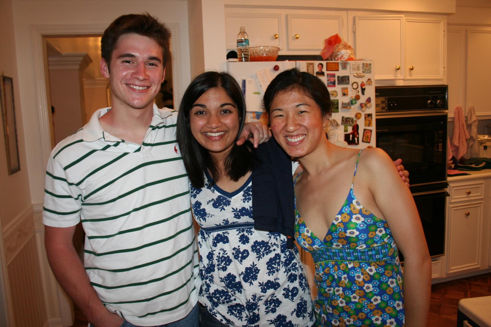 four people are posing for the camera in front of the kitchen door