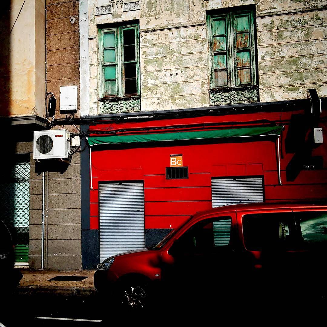 an old red and green garage next to a street
