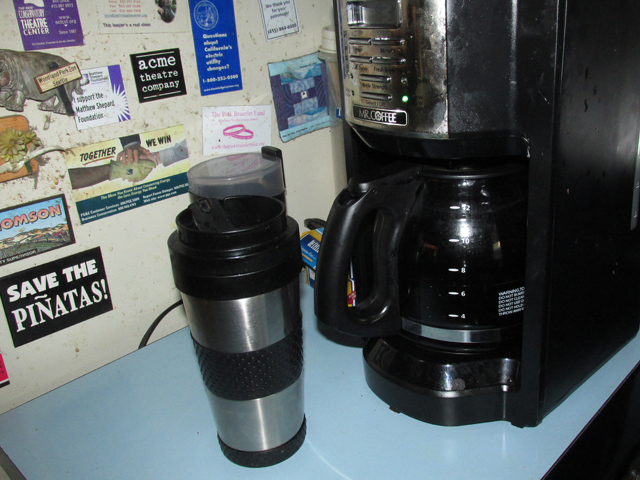 a coffee mug and black coffee maker on a blue counter