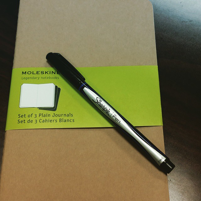 a pen sitting on a piece of paper that is next to some stamping