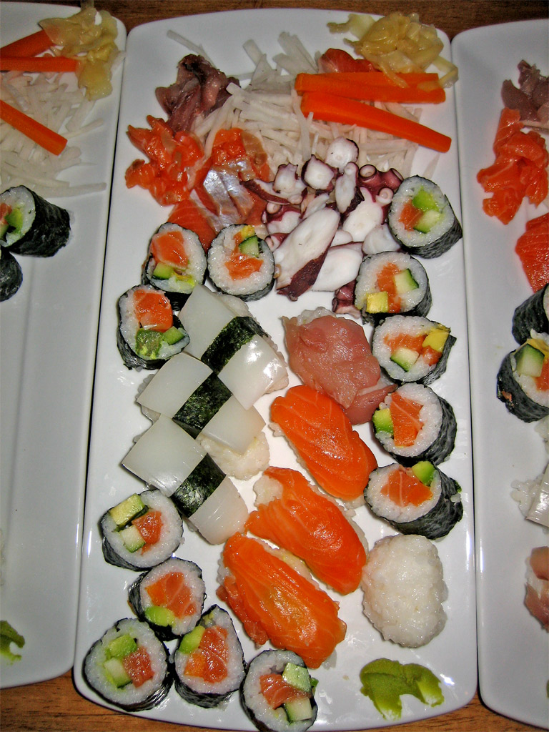 a collection of sushi displayed on long white plates