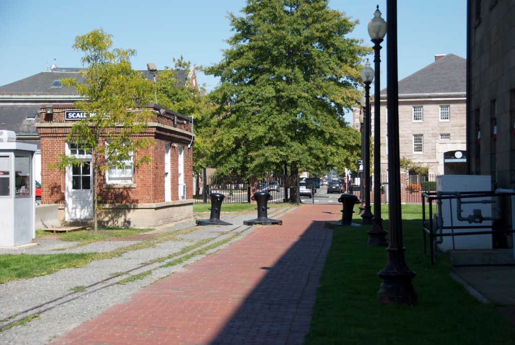 the tree - lined street has small brick buildings on both sides