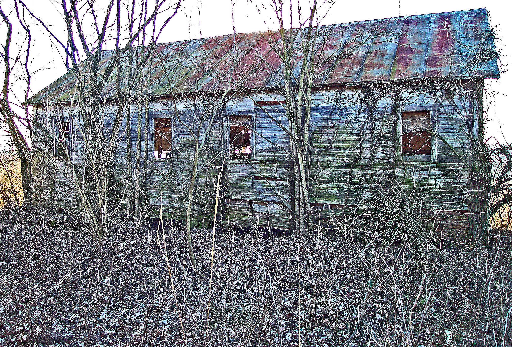 an old black building is standing in a field