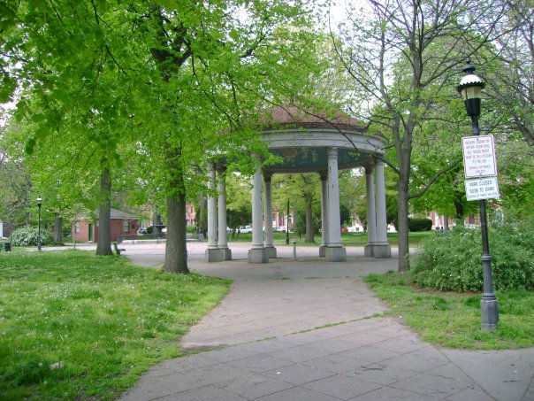 a gazebo with trees and signs sitting in the middle of the park
