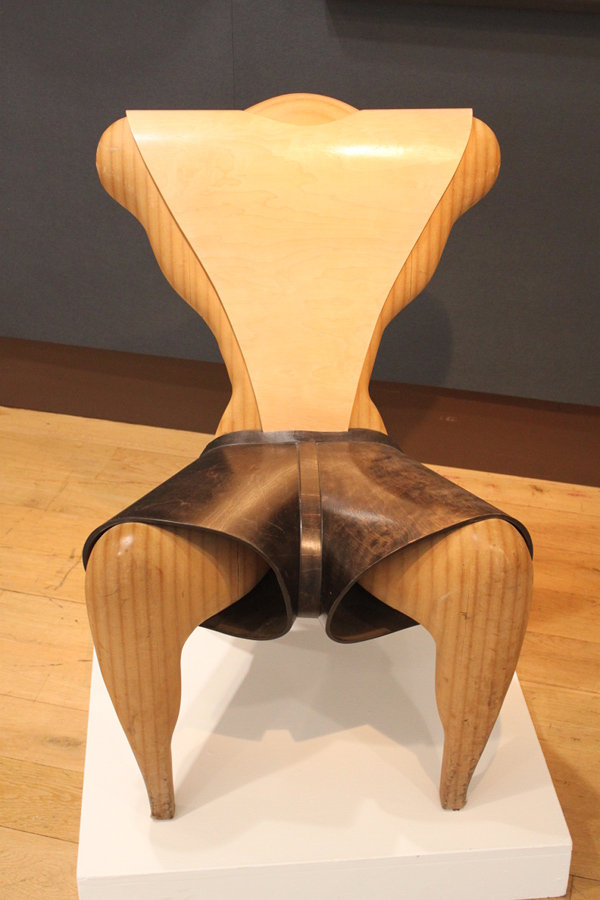 a wooden chair is on display on a white stand