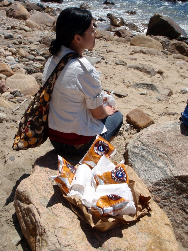 the woman is sitting on the rocks with her lunch