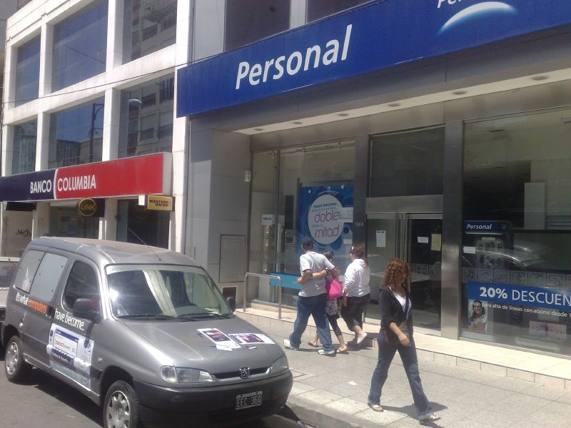 two people walking by a bank and a car