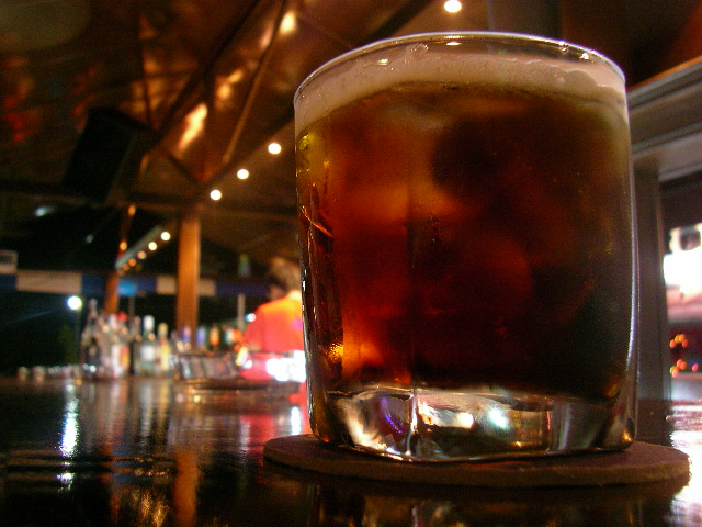 a drink sitting on a bar top near some lights