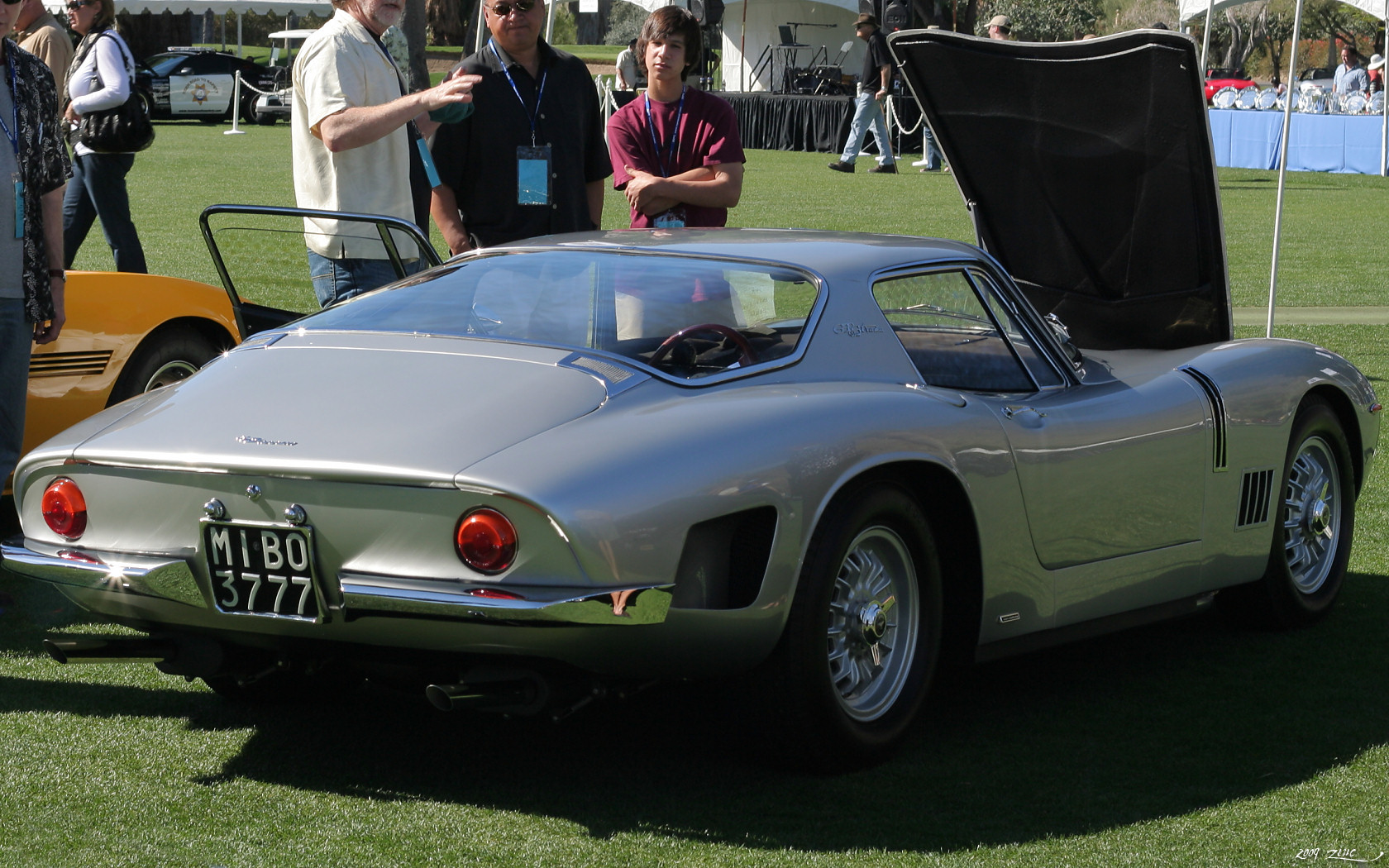 an older silver sports car is on the grass