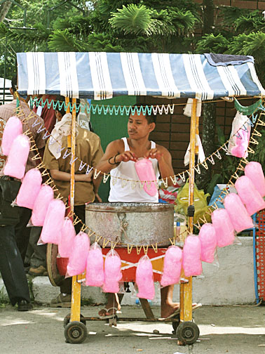 a man selling candy in a cart during the day