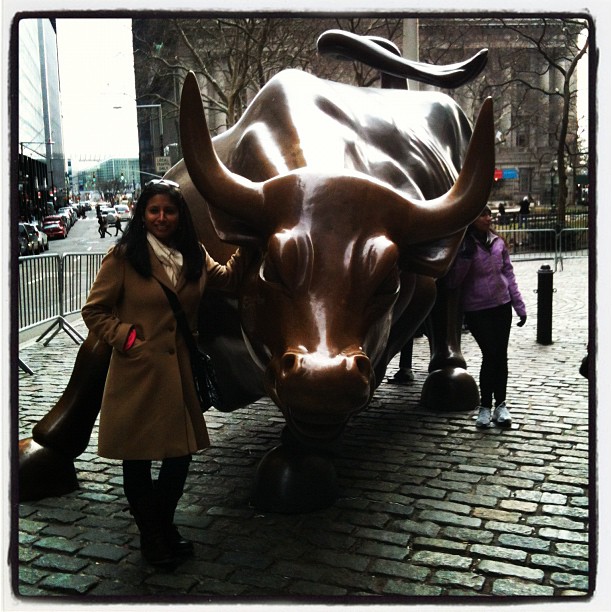 two people standing next to a statue of a bull