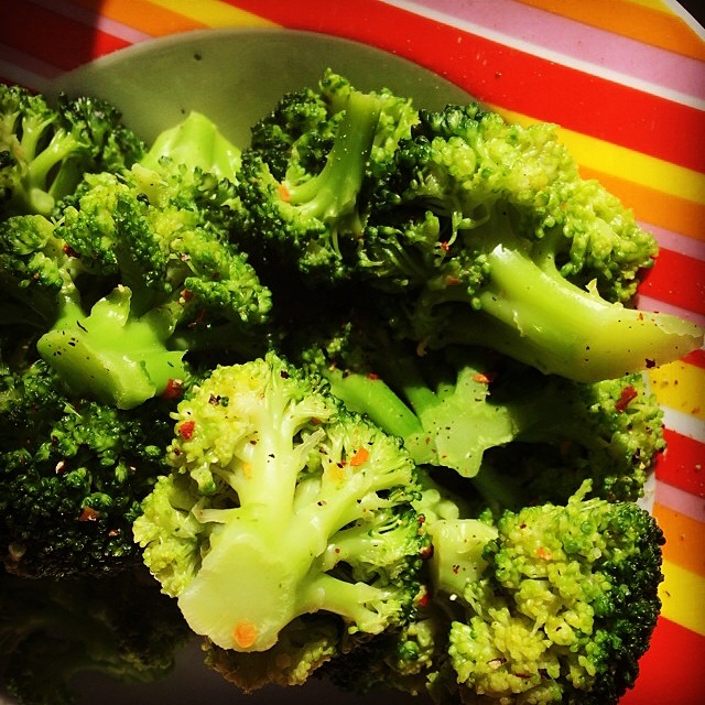 a plate that has broccoli on it with a colorful striped pattern
