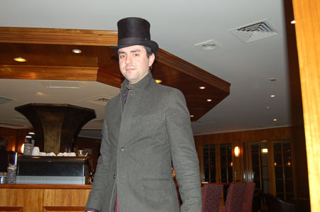 a man in a top hat and coat standing next to a wooden bar