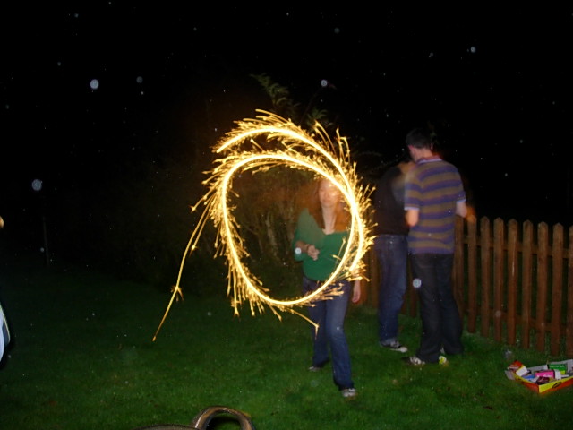 a person standing on the grass holding a sparkler