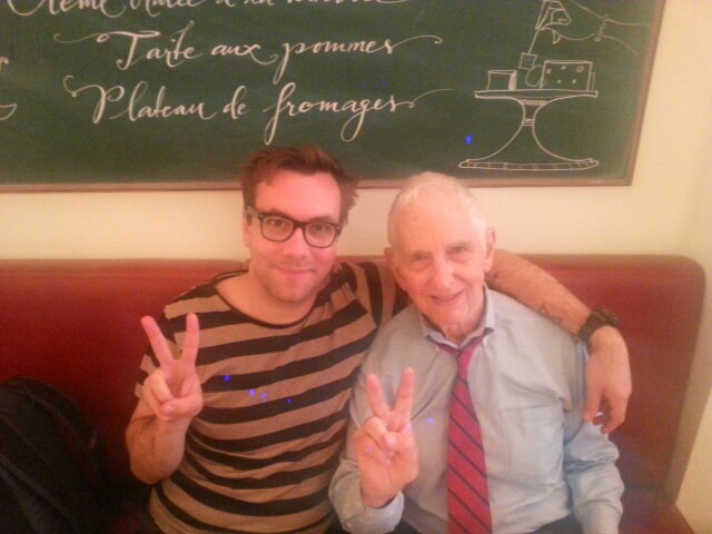 two men posing with peace fingers in front of a blackboard