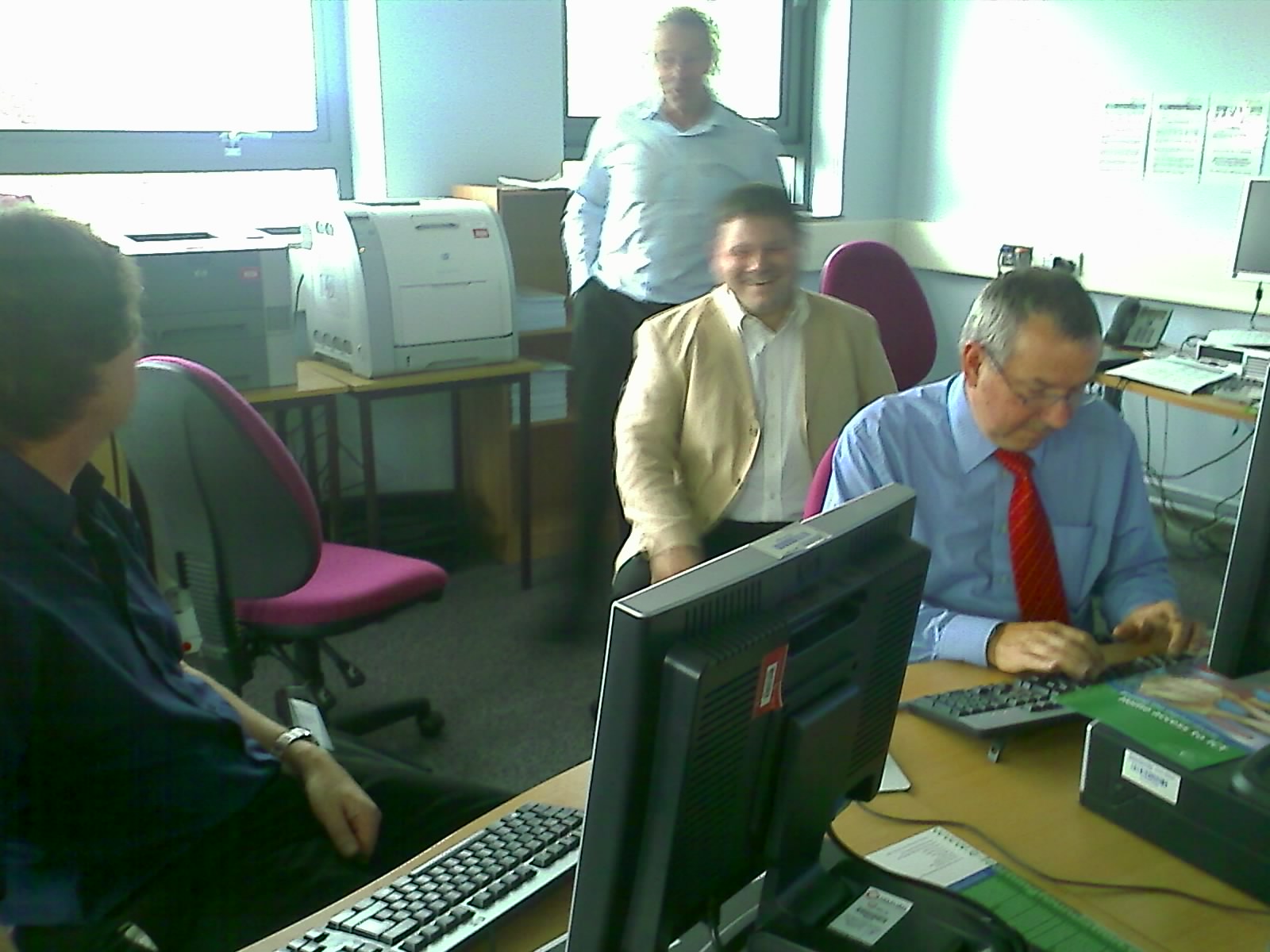 three people working in an office with one man on the phone
