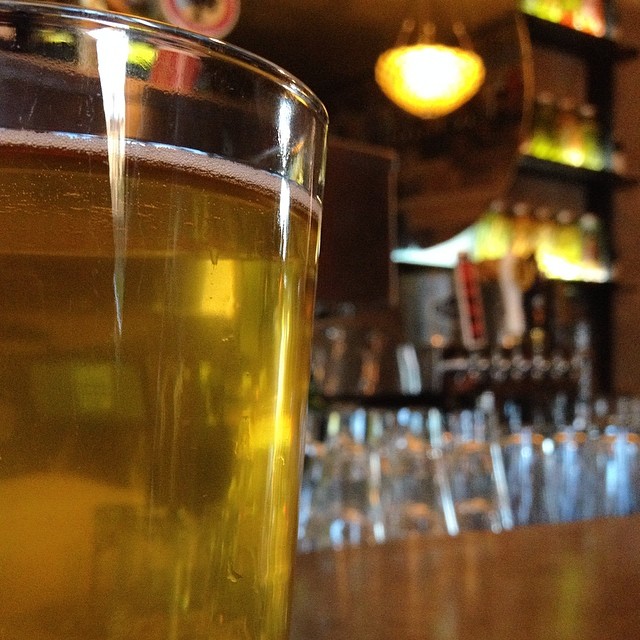 close up s of a beer in a pub with several empty bottles and a shelf on the bar