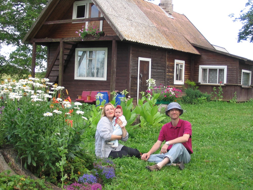 three people in front of a wooden house