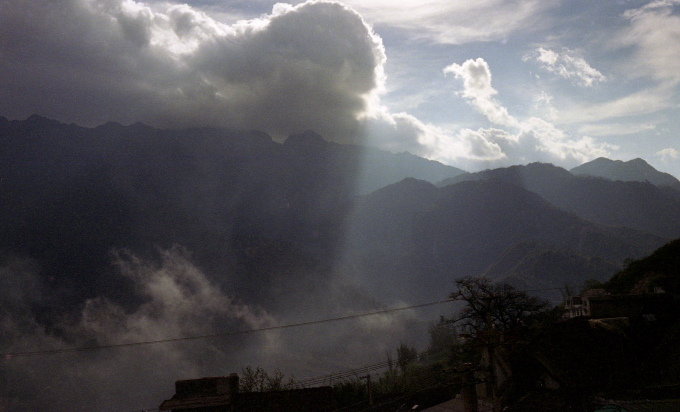 the sun shines on the mountain range with clouds