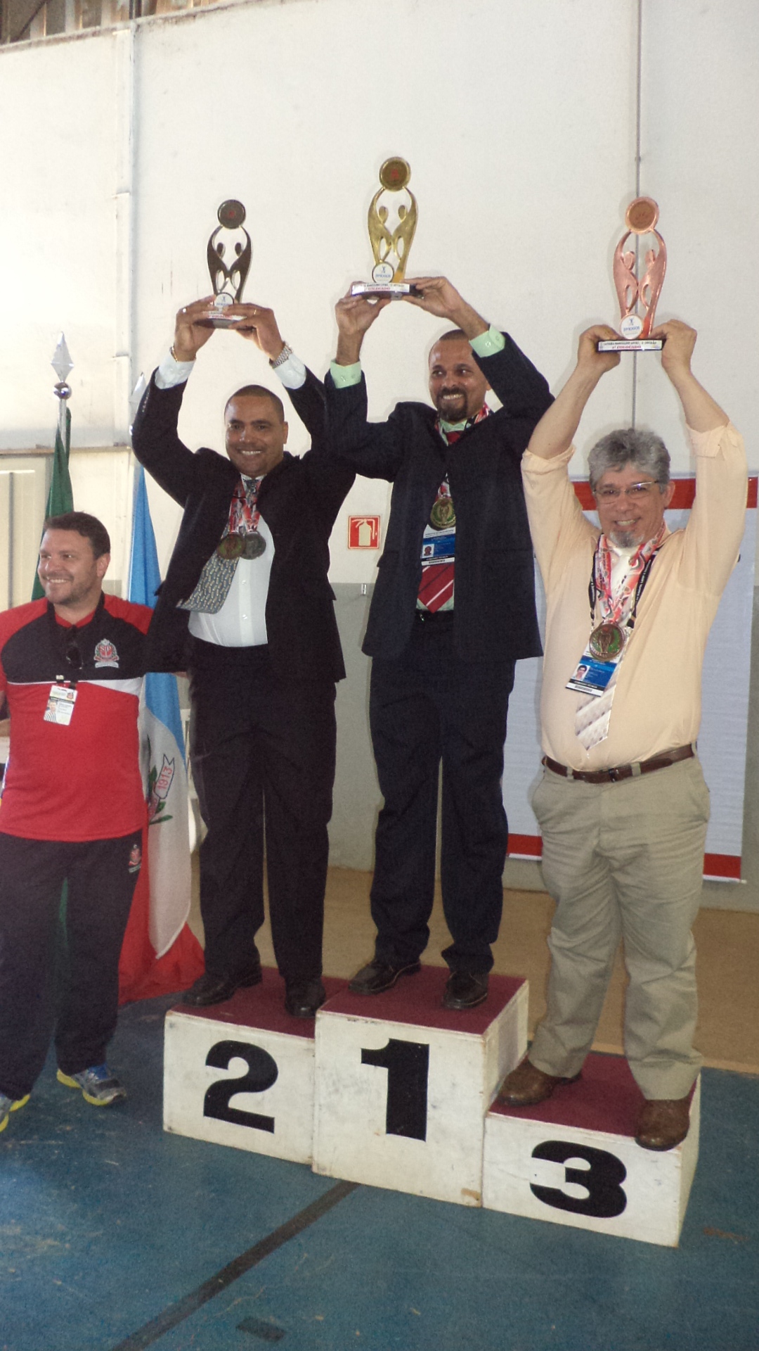 four men on the winners podium holding up trophies