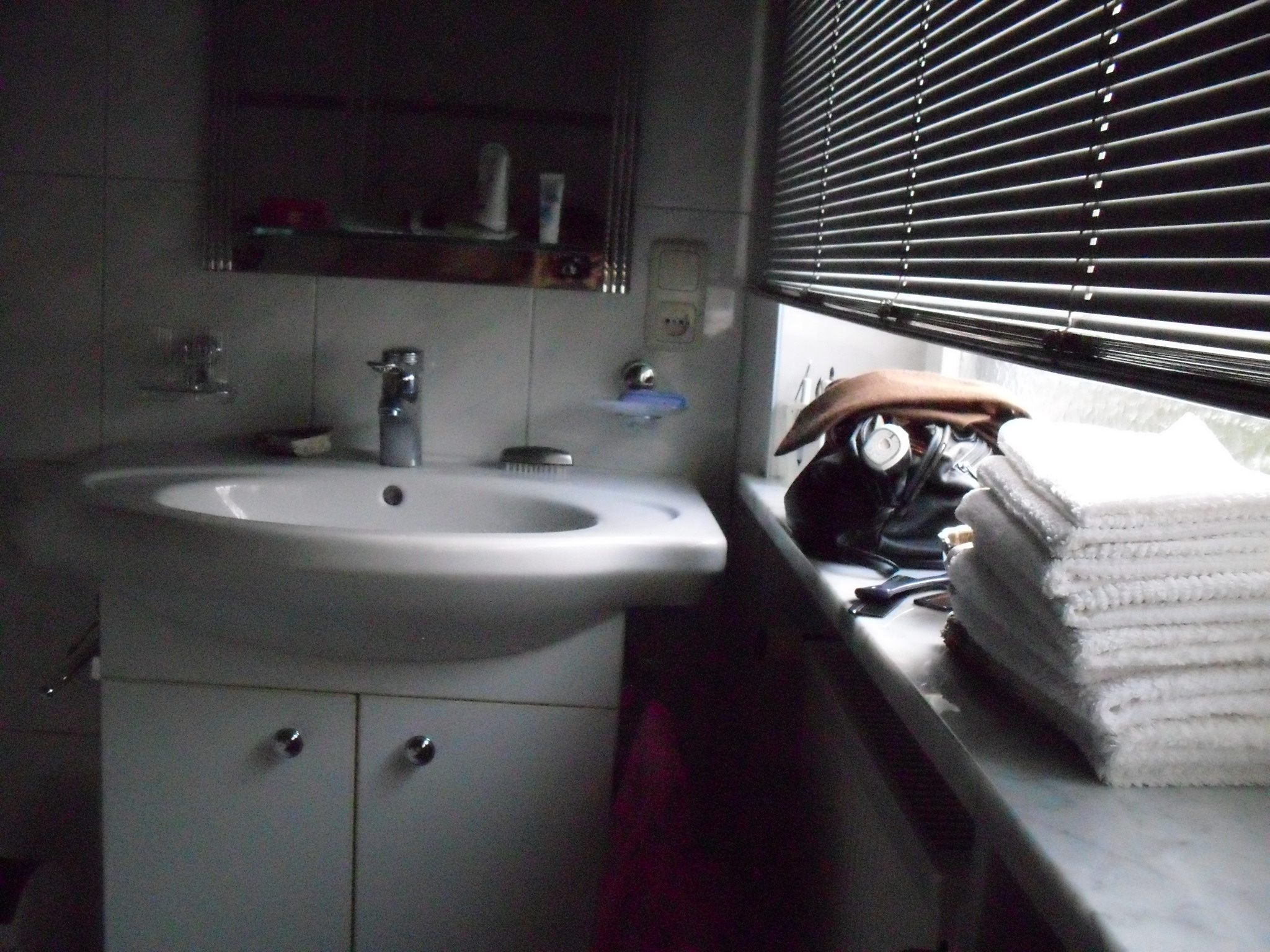 a bathroom with a large window, sink and stacked towels