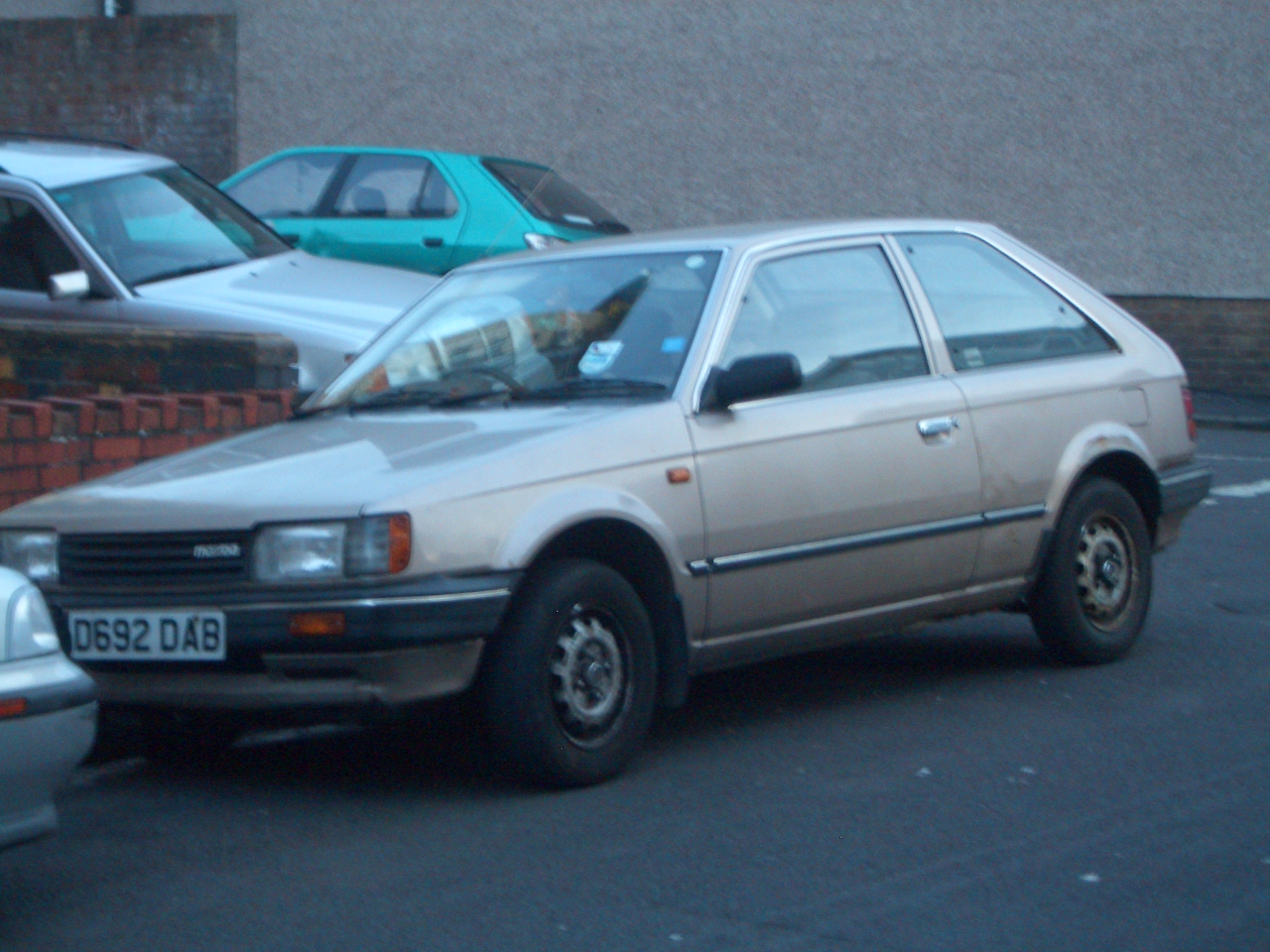 an old, dirty car sits in a parking lot