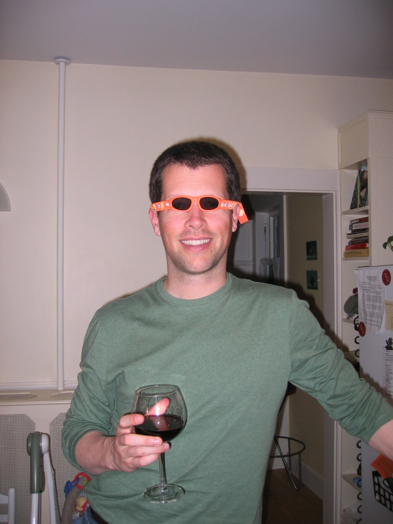 a person wearing glasses and holding a glass