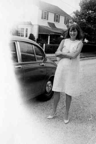 a woman wearing a white dress standing next to a car