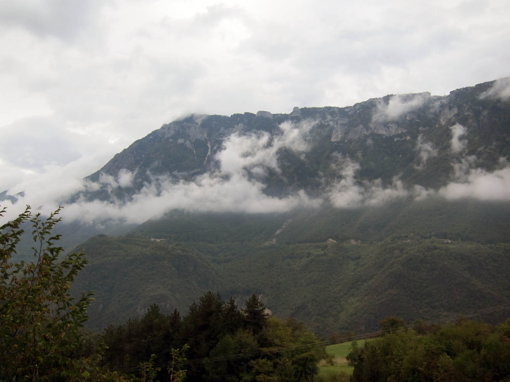 the clouds are covering mountains and trees