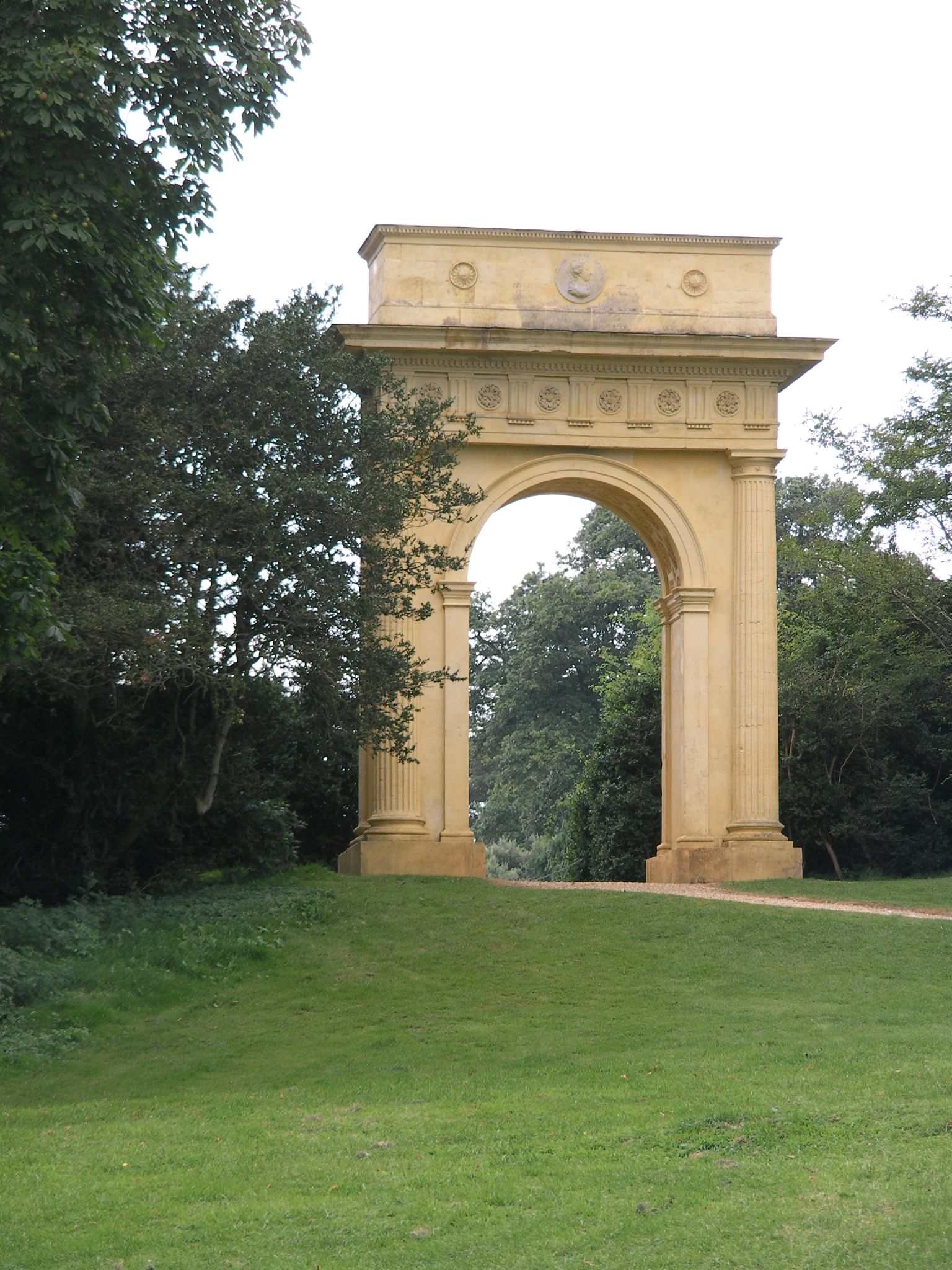 a grassy area with trees and an ornate archway