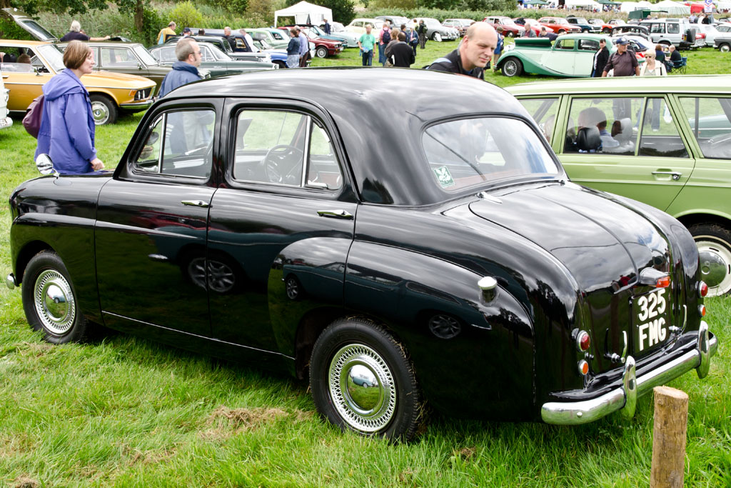 a vintage black car is parked on the grass