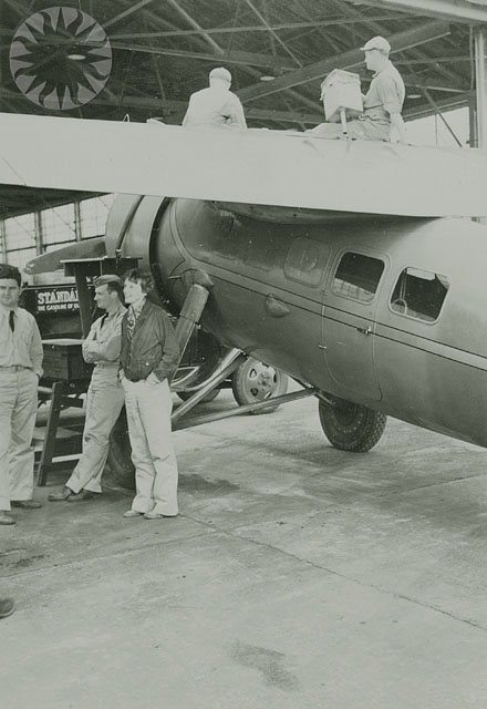 a group of men standing outside of a very old plane