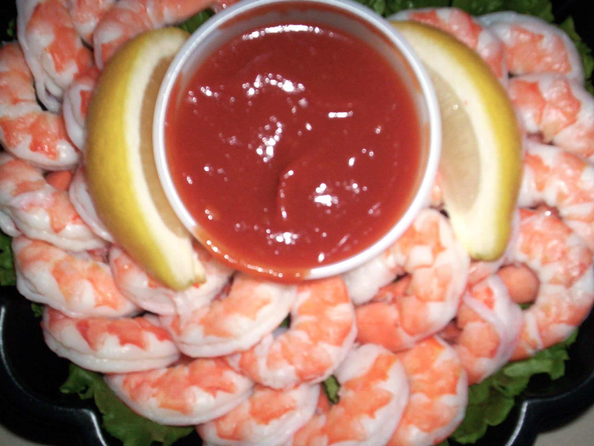 some shrimp and lettuce on a platter with a dipping sauce