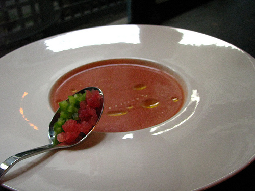 a spoon with a bowl of tomato soup