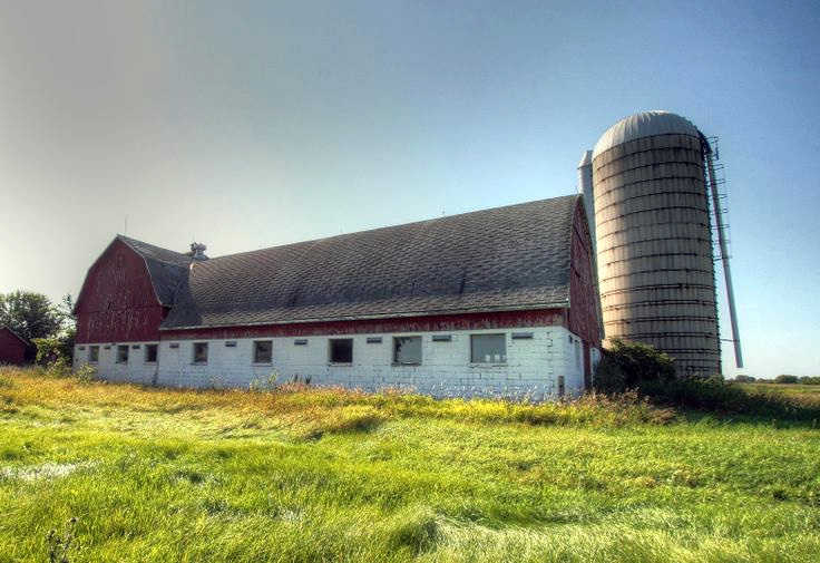 this barn sits empty in the middle of a grassy field