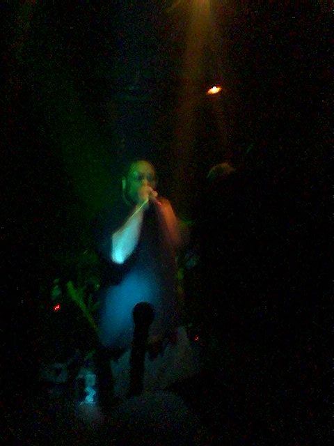 man in white t - shirt singing at a club