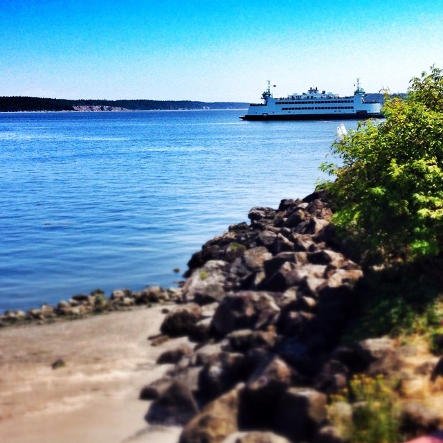 the large ship is docked by the rocky shore