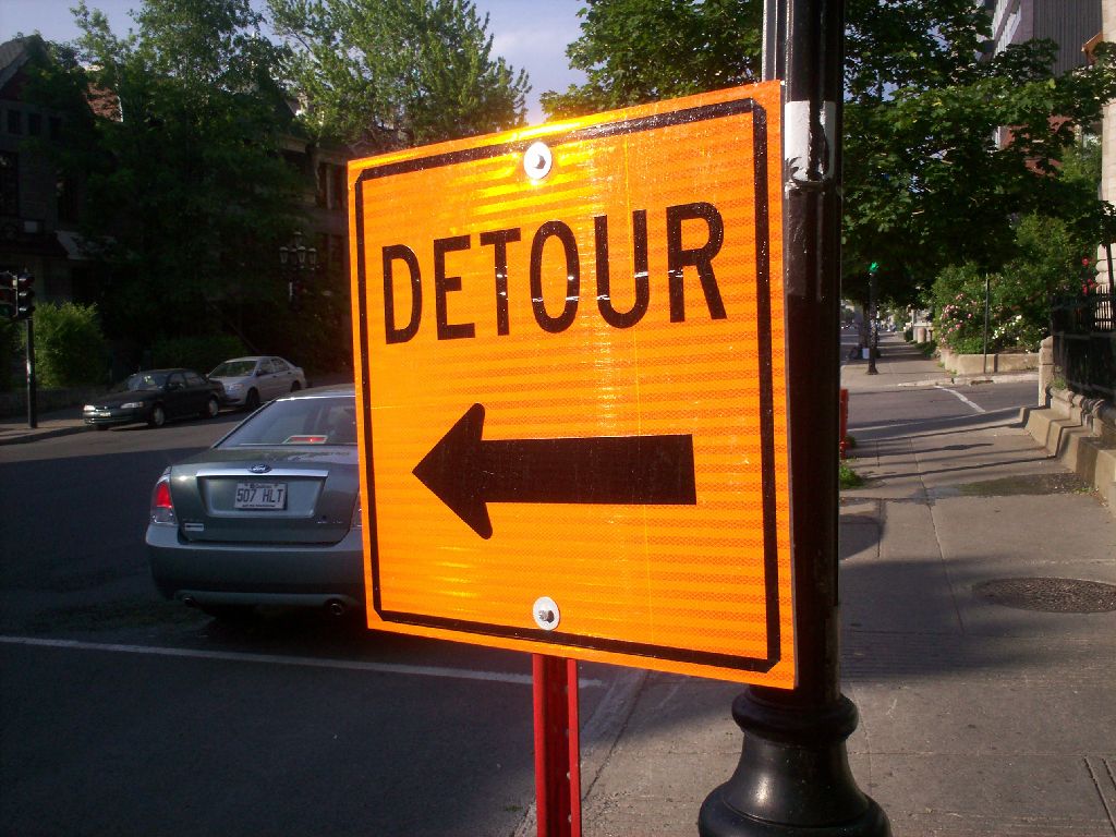 an arrow and detour sign on the side of the street