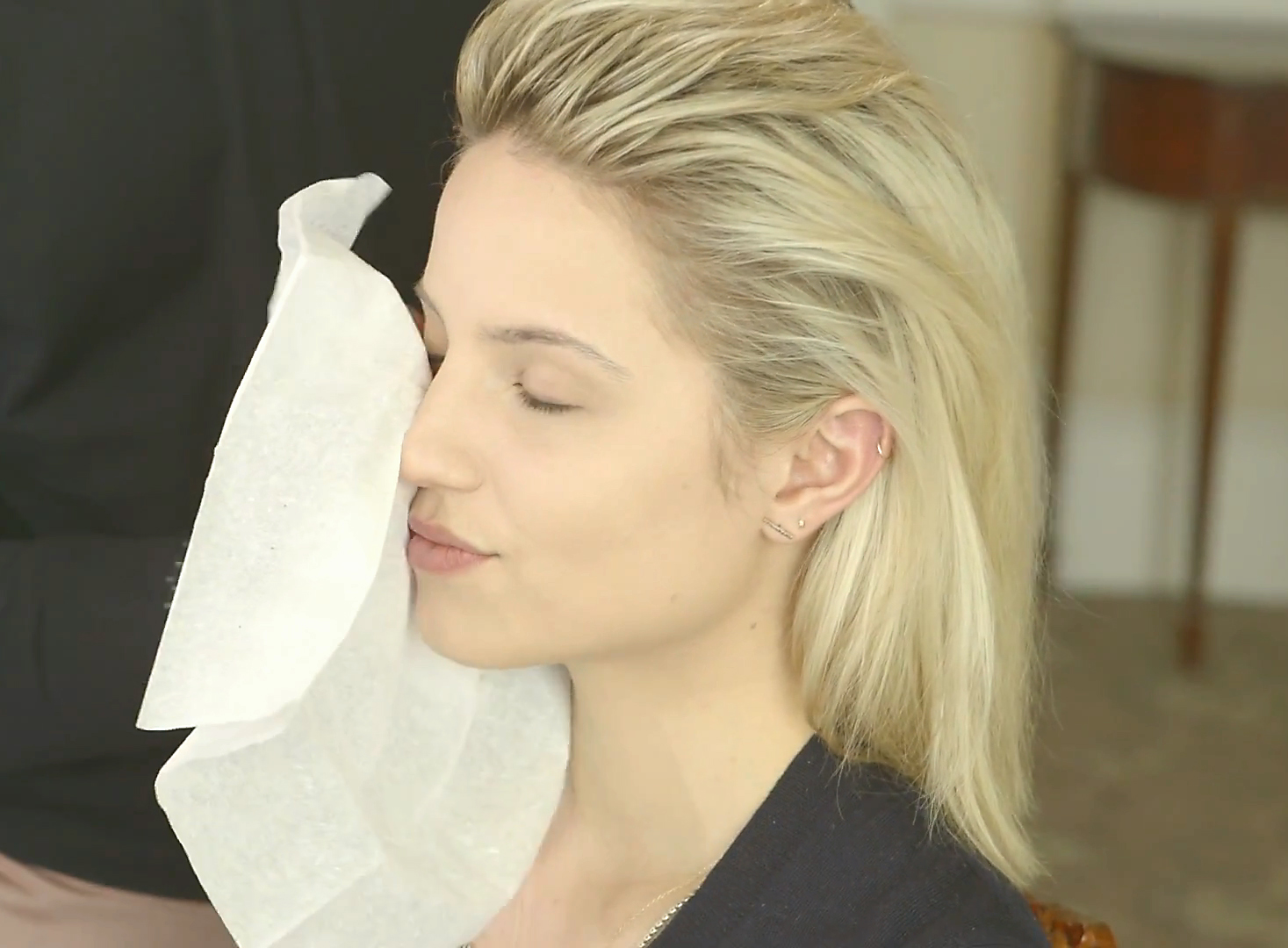a blond woman with her eyes closed and a roll of tissue is covering her face