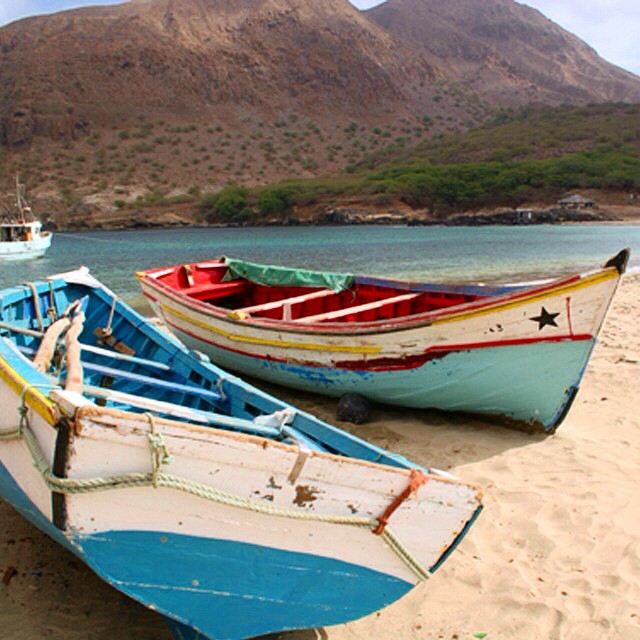 three small boats that are sitting in the sand