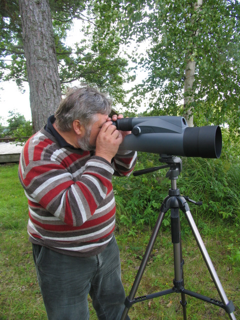 a man in striped shirt looking through telescope