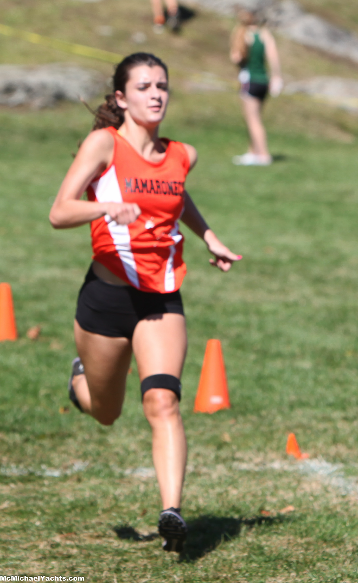 a girl running across a field with orange cones