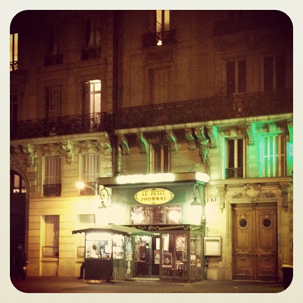 a building at night with lit up signs and an awning on the second floor