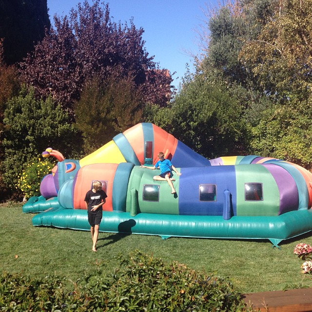 a girl in a black dress standing on an inflatable jump castle in a garden