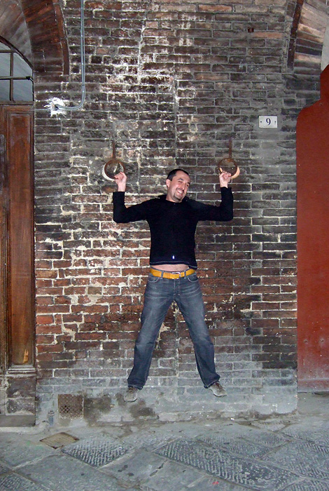 a man jumping in the air near a building with an old fashioned clock hanging from the ceiling