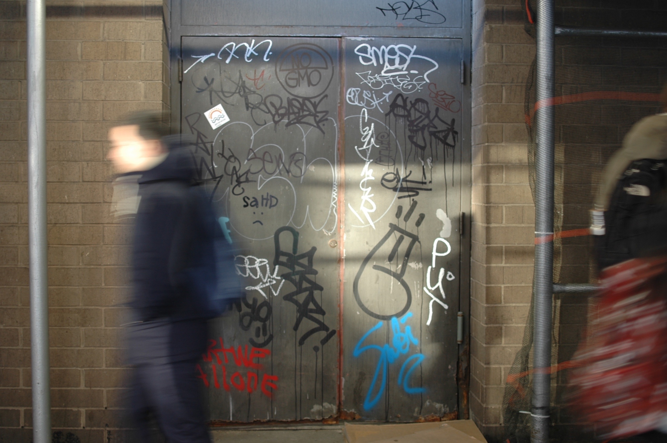 a man walking past a building covered in graffiti