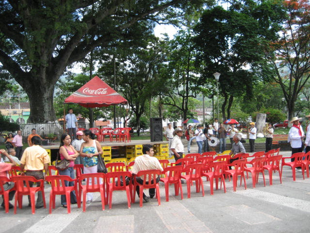 an outdoor dining area is lined with red plastic chairs