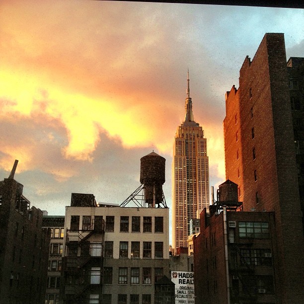 an orange sky is seen behind a tall building