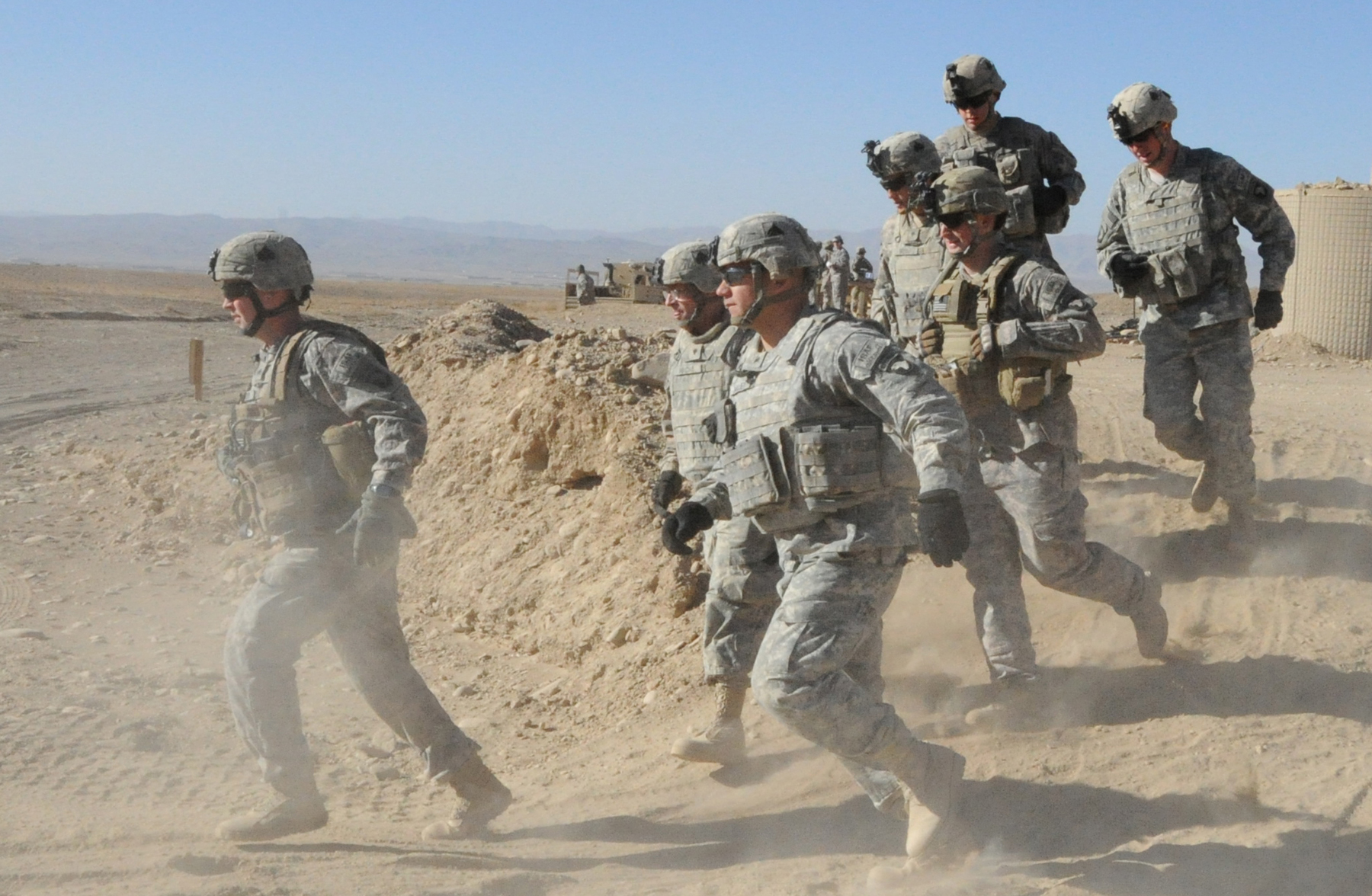 several military men in desert setting with one man in motion