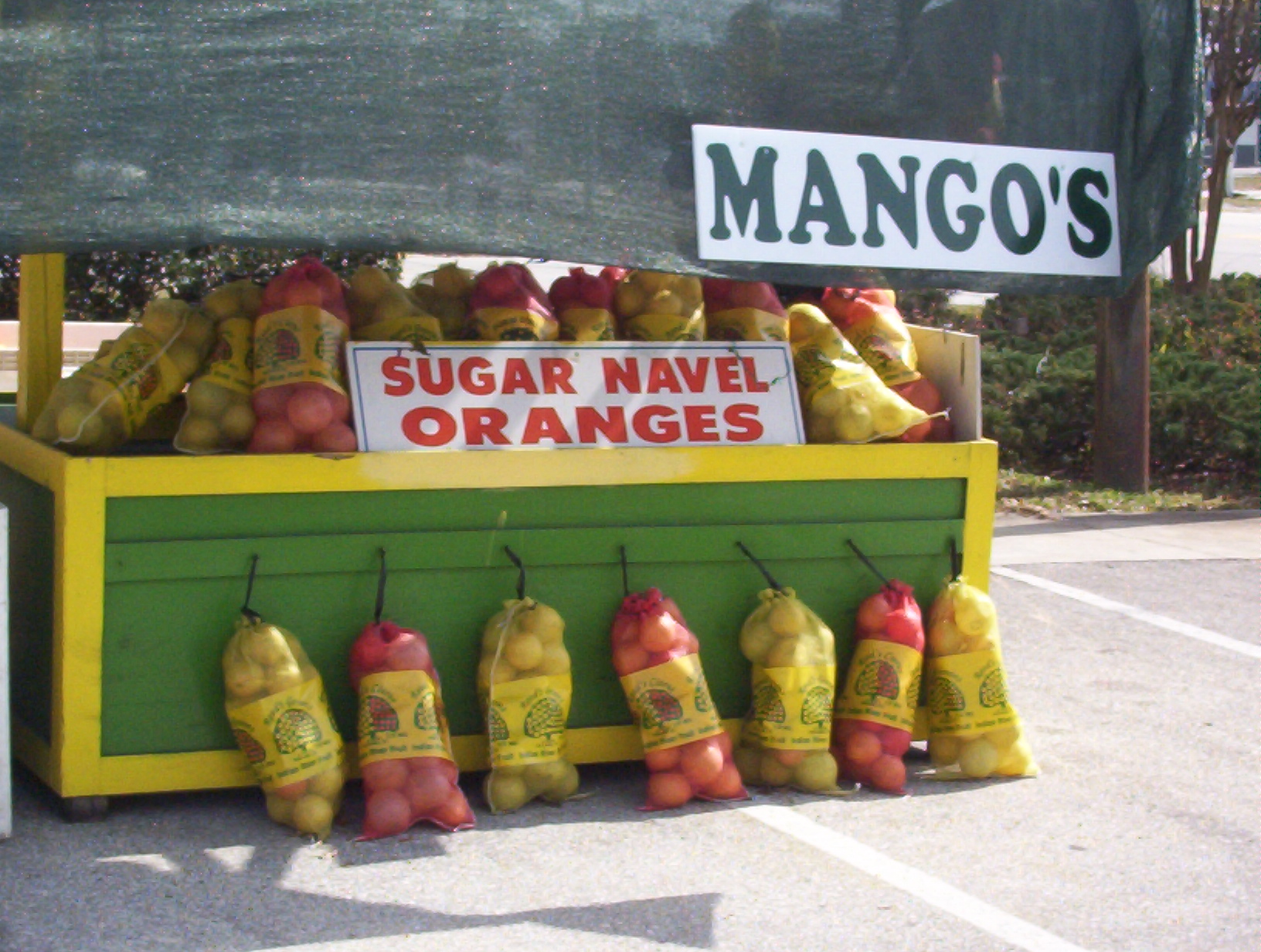 a fruit stand on a street with mangos for sale